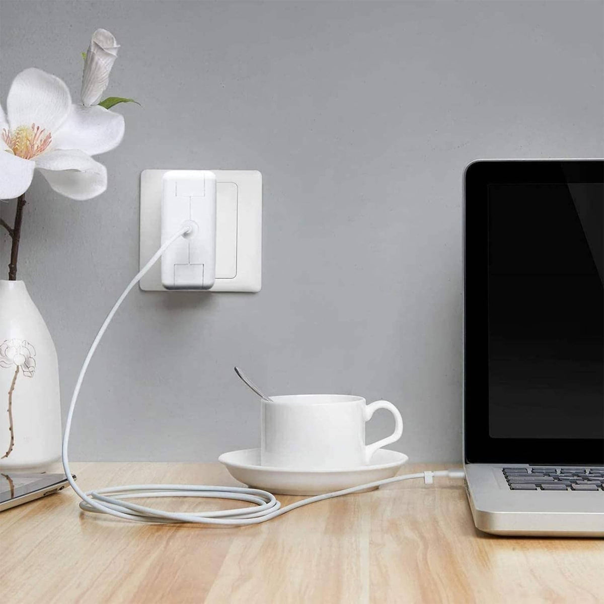 White laptop charger adapter plugged into a wall outlet with cable