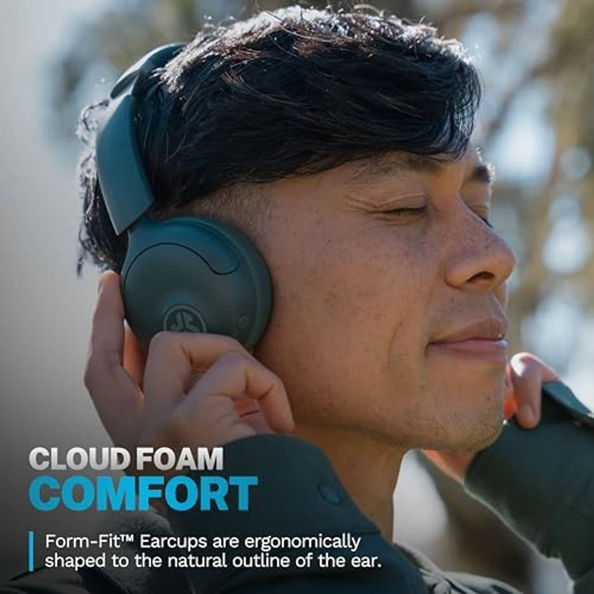Sage green on-ear wireless headphones worn by a person with hand near earcup