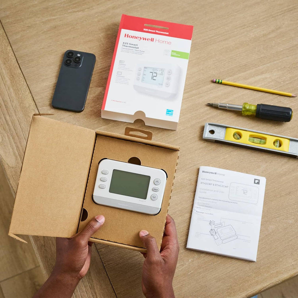Smart thermostat unboxed from retail packaging, with documents on a table