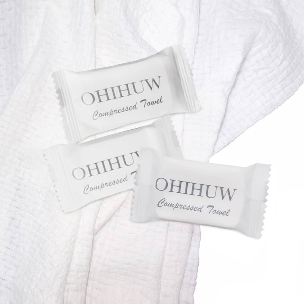 White compressed disposable towels with branded packets, neatly folded stack
