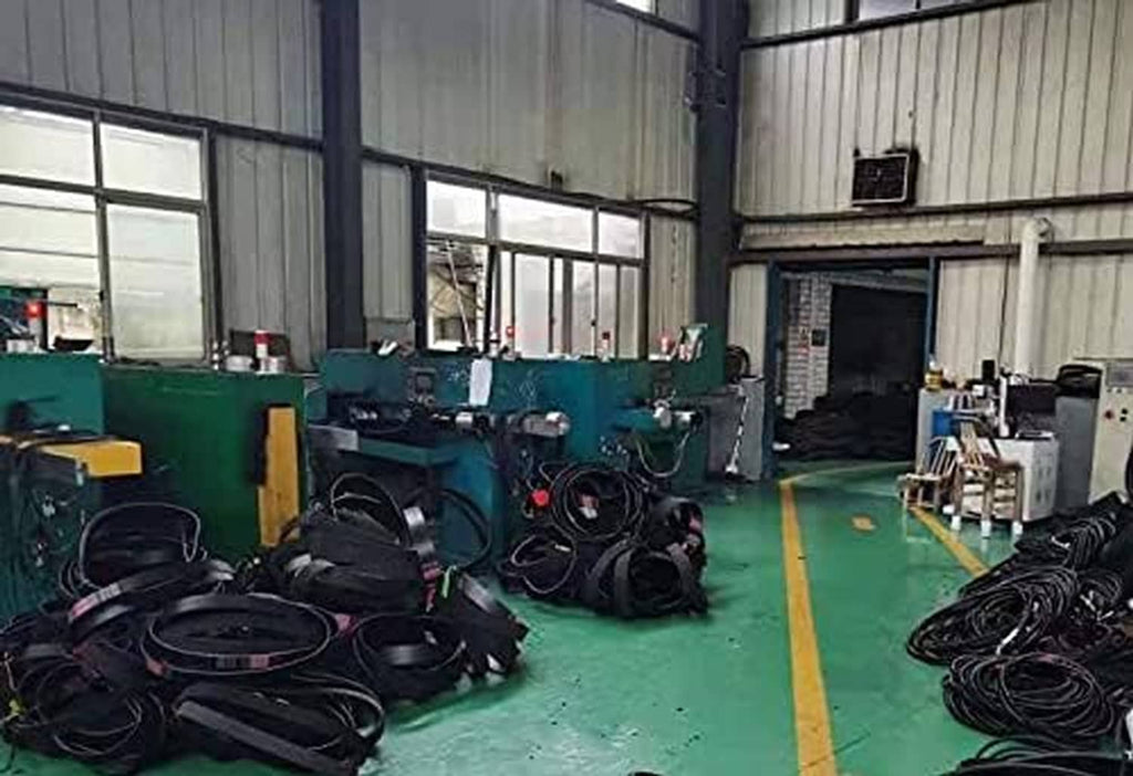 Workshop floor with coiled black belts beside green industrial equipment