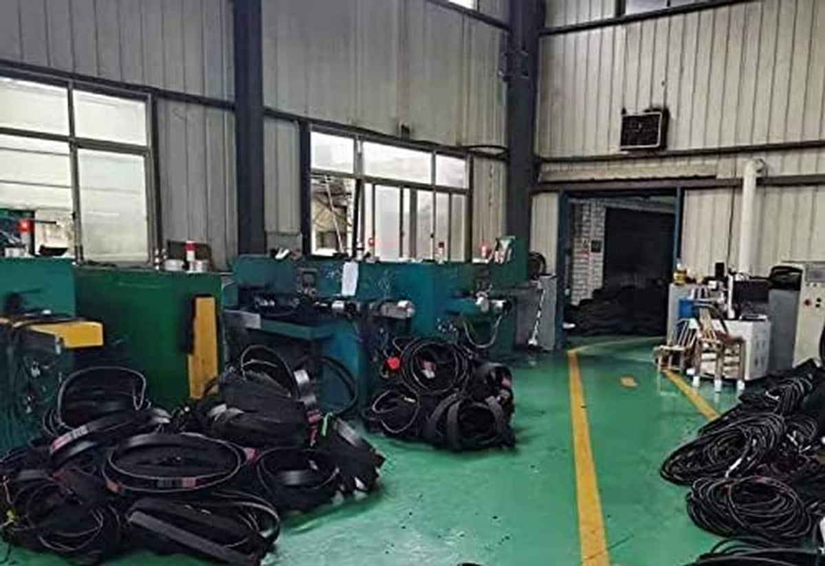 Workshop floor with coiled black belts beside green industrial equipment