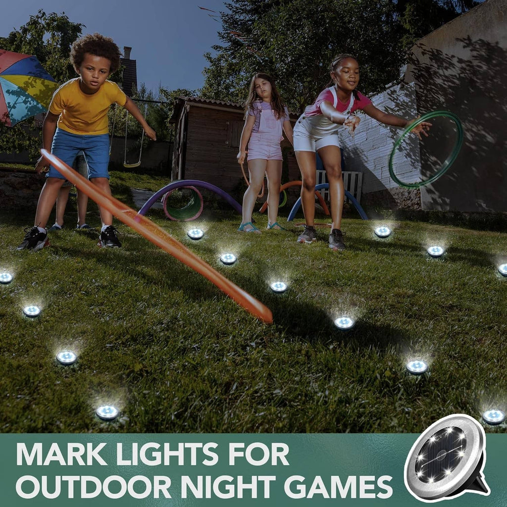 Mini solar ground lights, cool white, glowing round disks in yard during outdoor games