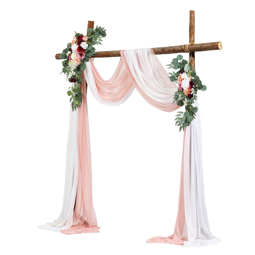 Faux wedding arch with wooden crossbar, pink floral accents, and flowing sheer drapes