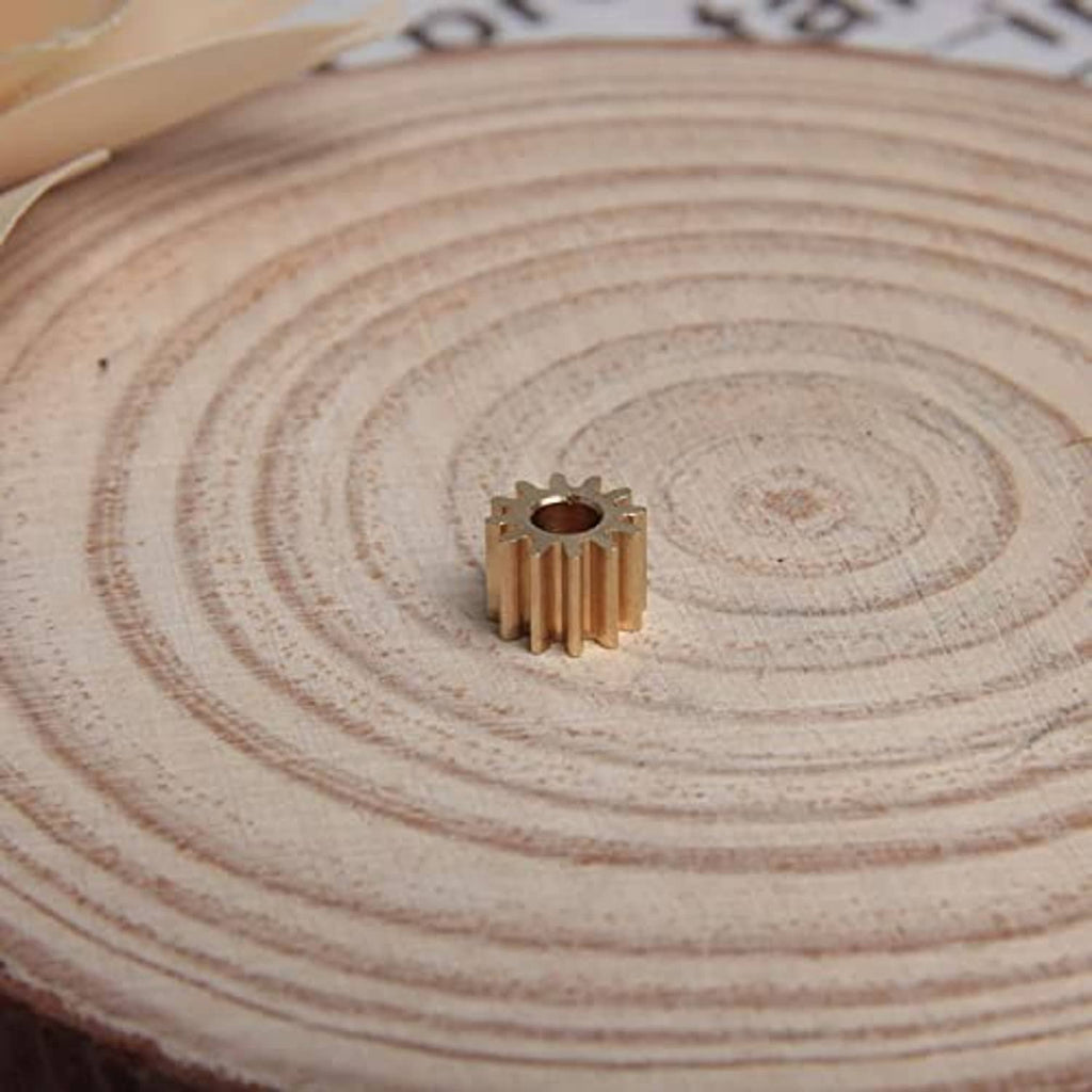 Copper 12-tooth spur gear with 3 mm bore, centered on a wooden slice
