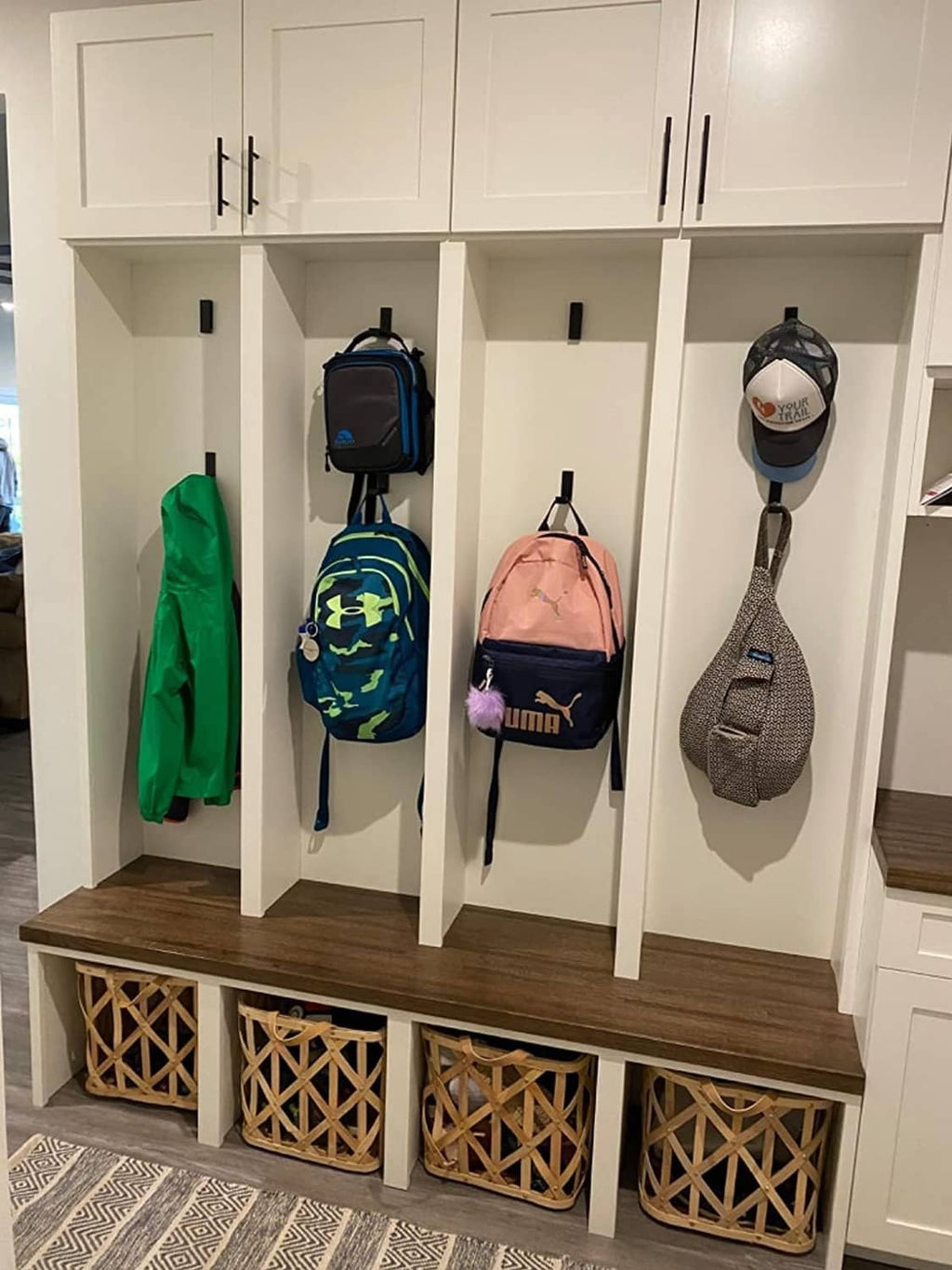 Black folding wall hooks mounted inside a cabinet for hanging coats and bags