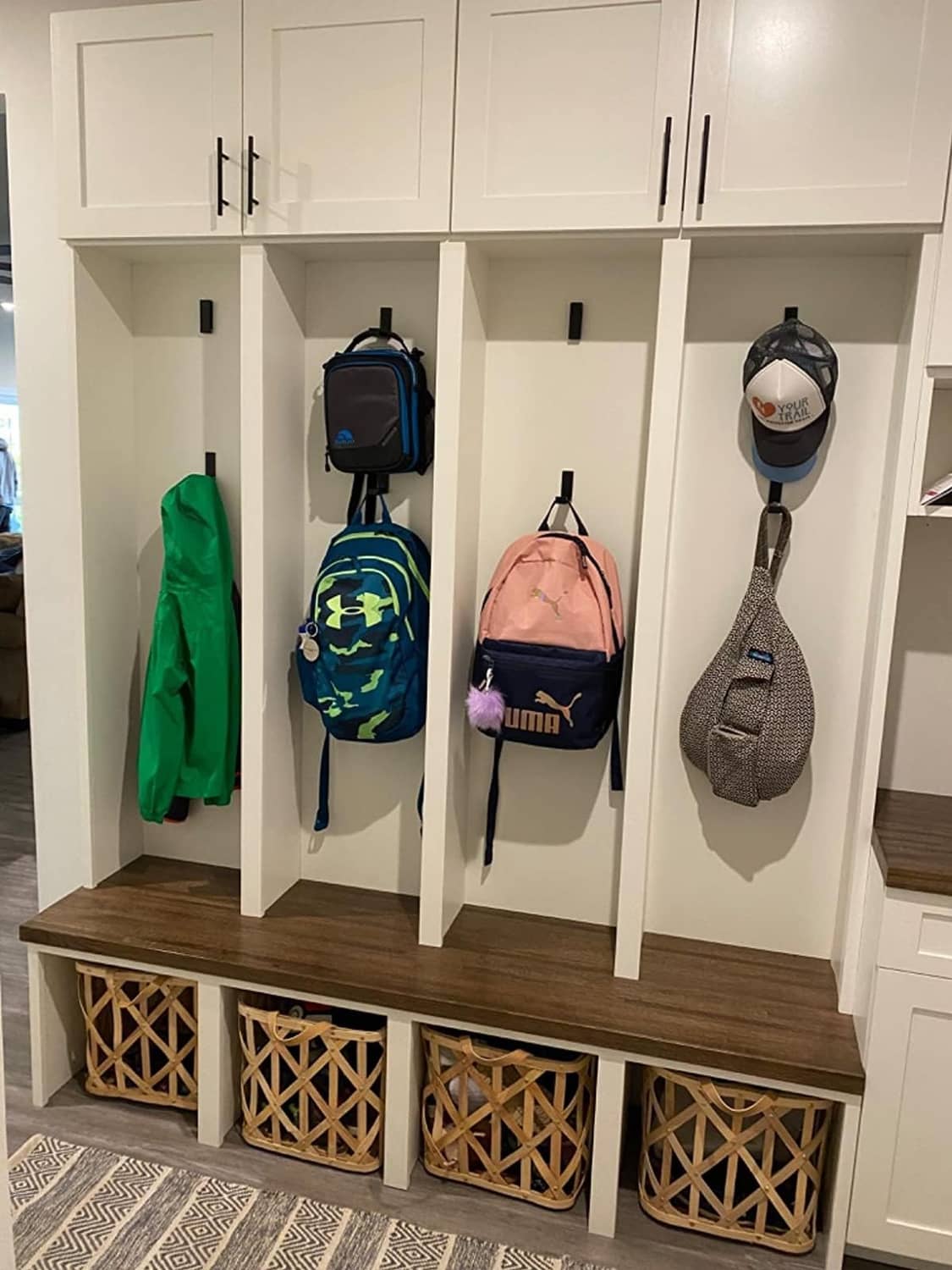 Black folding wall hooks mounted inside a cabinet for hanging coats and bags