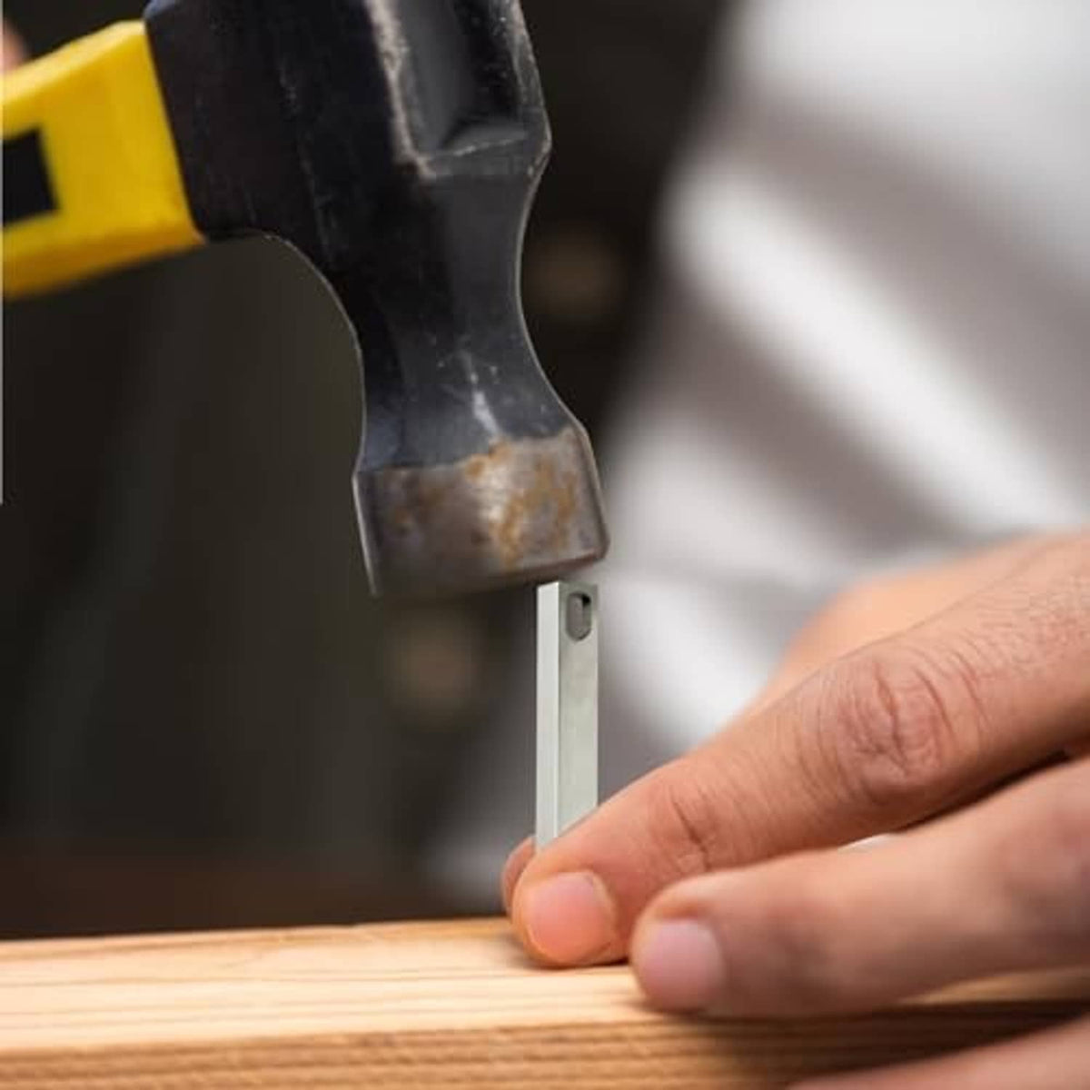 Metal prybar wedged under a wooden board for lifting