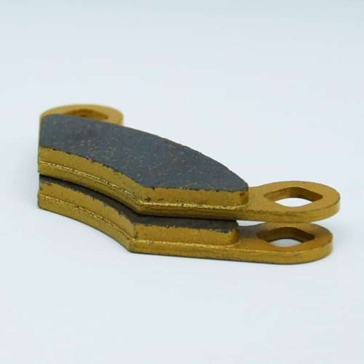 Ceramic brake pad with dark gray face, gold backing, and two mounting holes