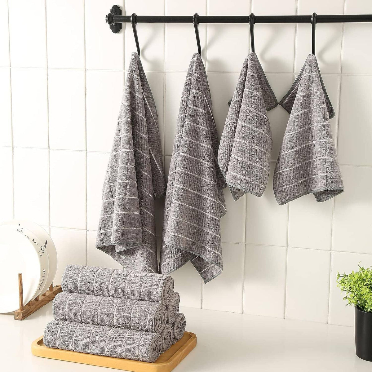 Grey microfiber towels hung on a bar, folded stacks on a wooden display tray.