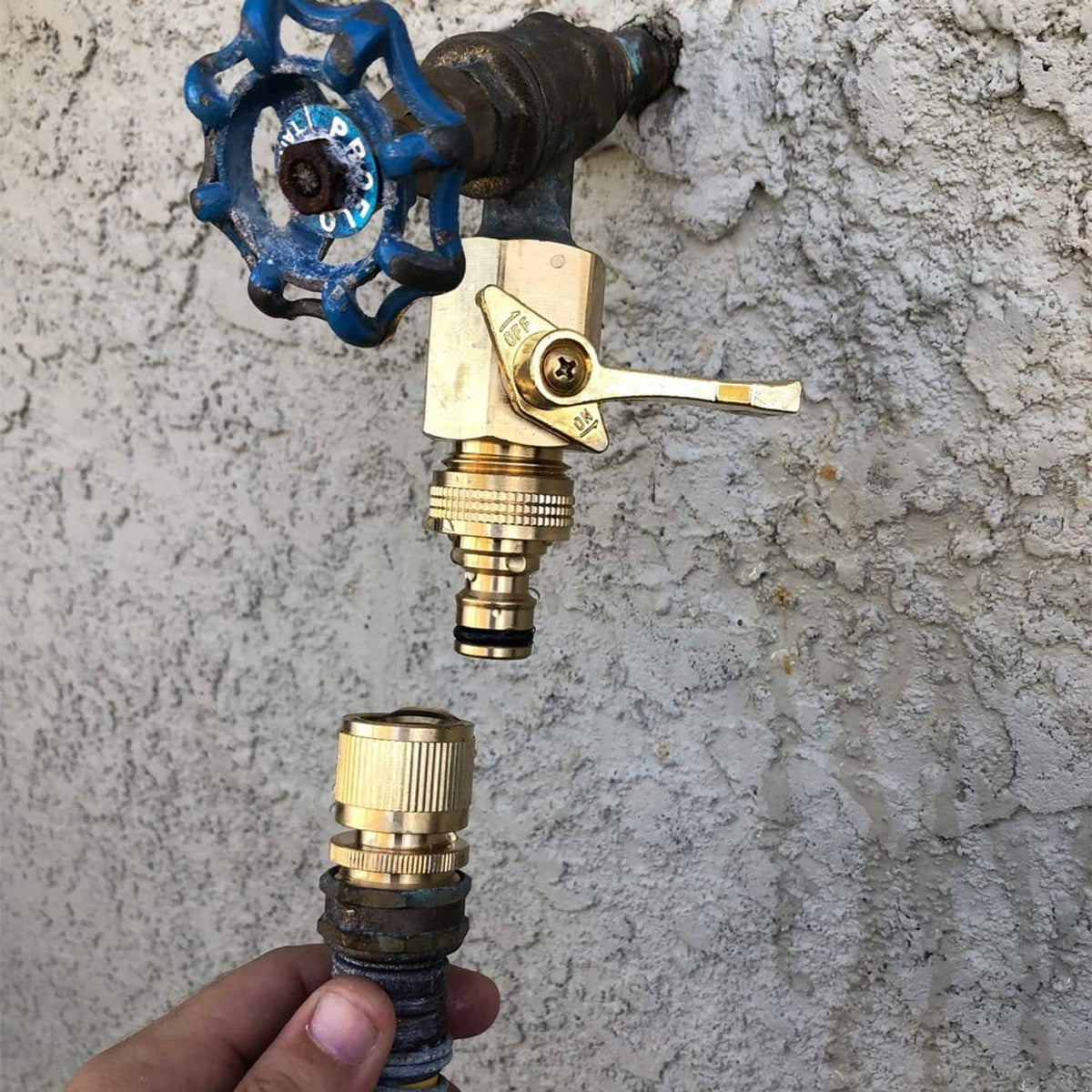 Brass quick-connect hose adapter installed on outdoor spigot with hand-held plug end