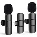 Two black mini wireless lavalier microphones with foam windscreens and clip mounts