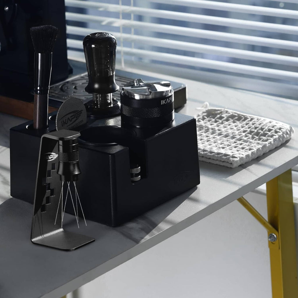 Black espresso tamper station with tamper, distributor, and cleaning tools on counter