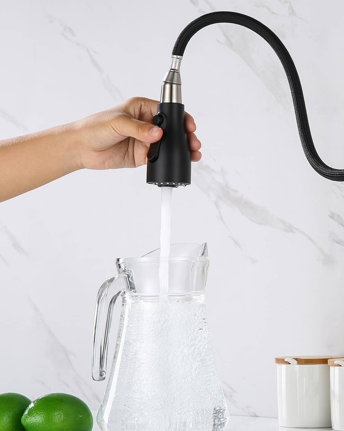 Matte black kitchen faucet sprayer head releasing a steady stream into a container.