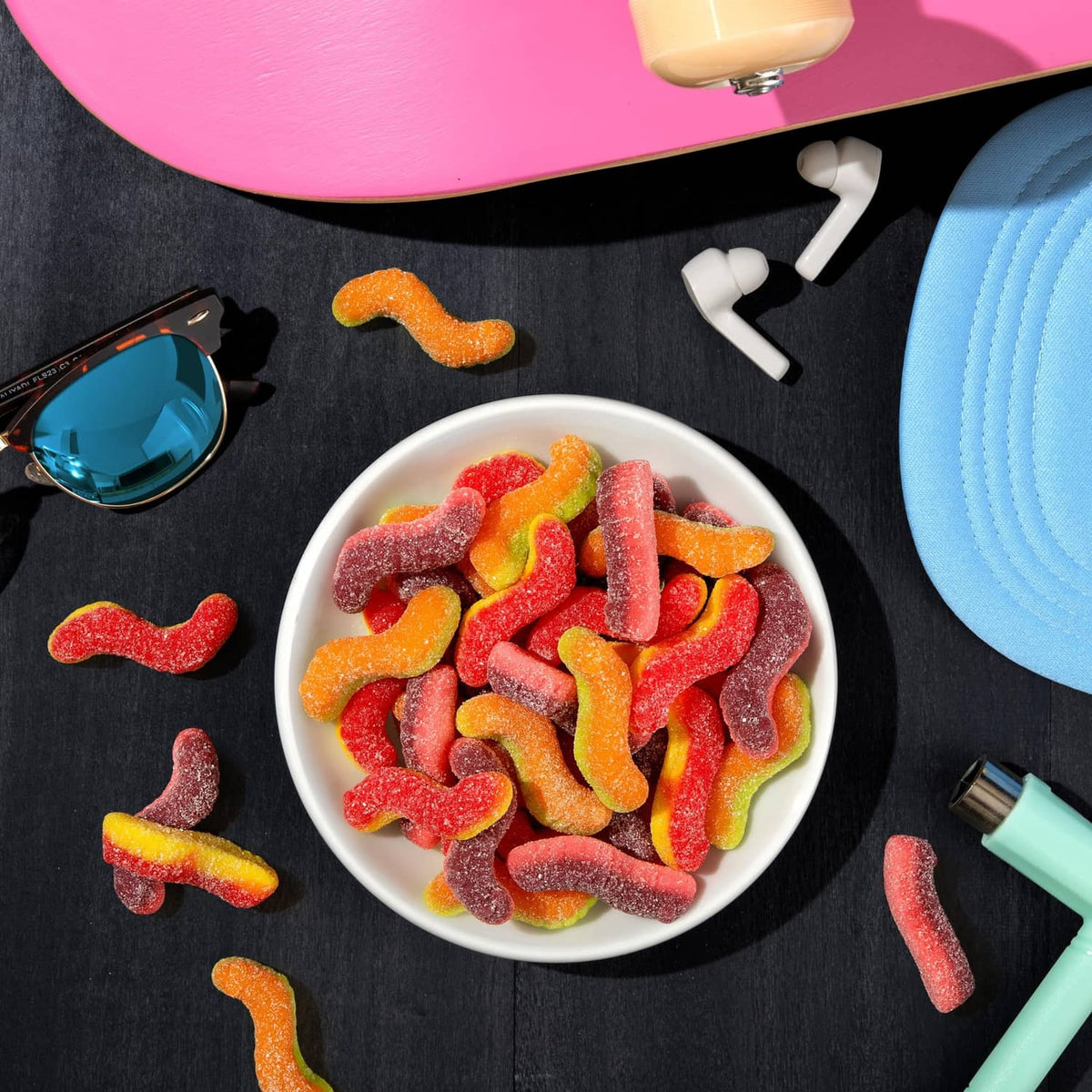 Bowl of mixed sour gummi crawlers candy pieces with scattered candies