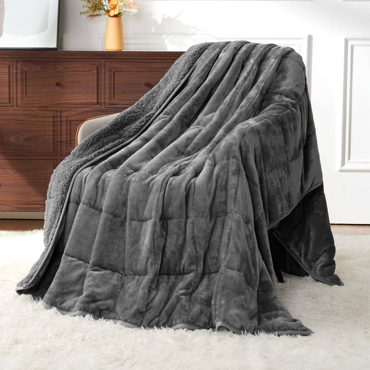 Grey weighted blanket draped over a bed, soft quilted texture