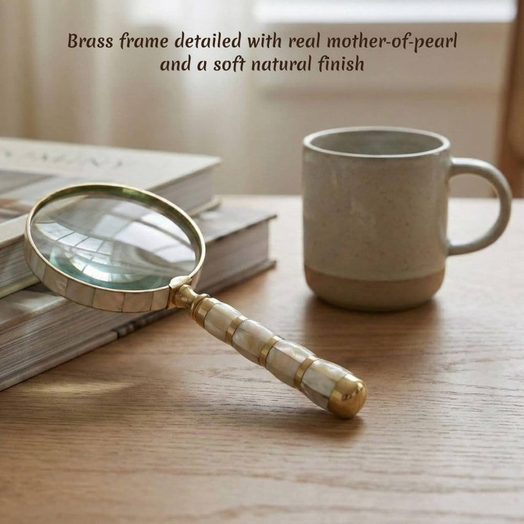 Mother-of-pearl magnifying glass with brass frame and striped handle on books