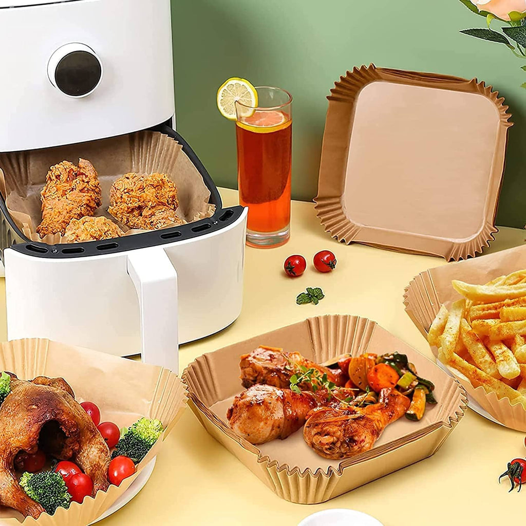 Square paper air fryer liners holding chicken and fries, wood-brown disposable sheets