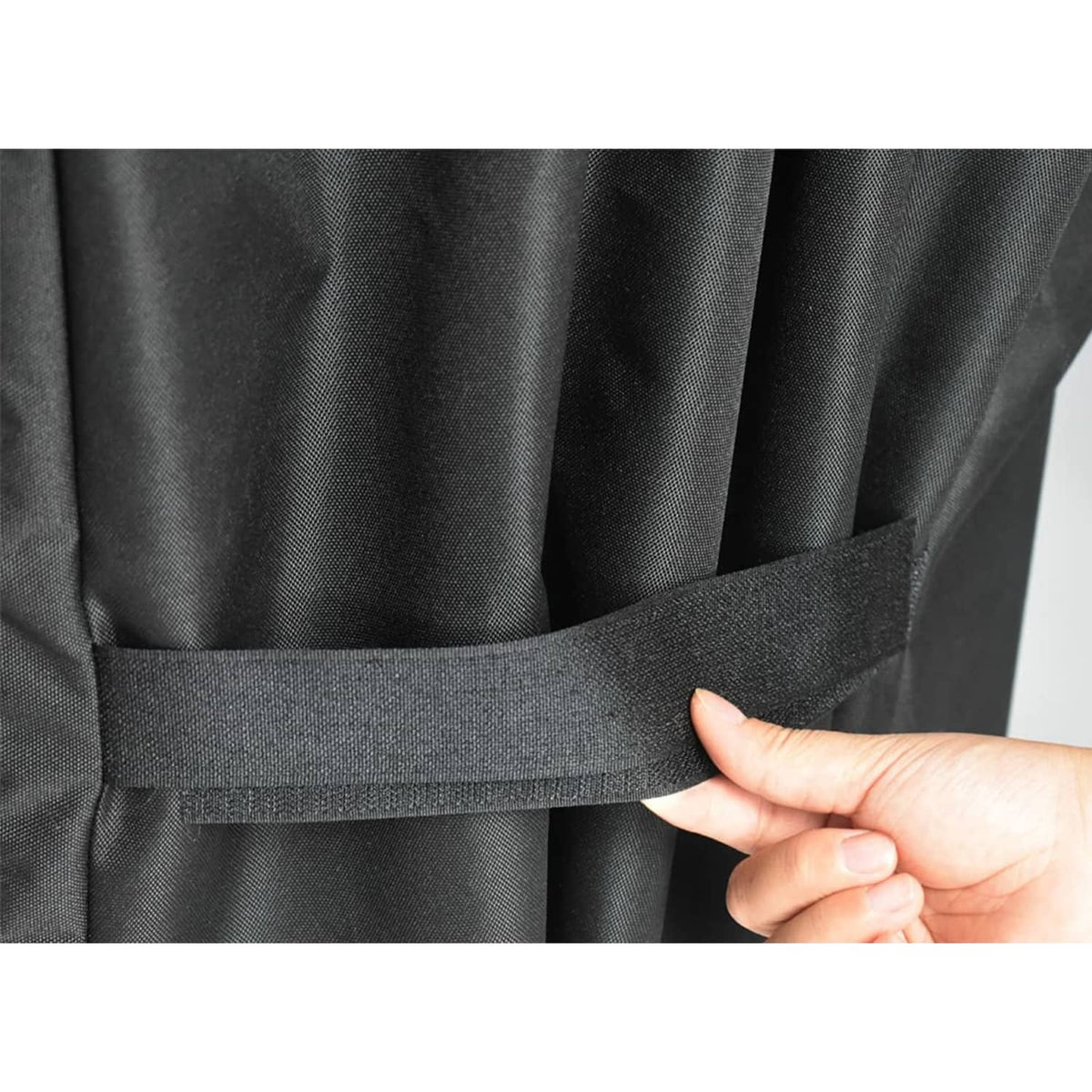 Black grill cover with adjustable fastening strap and hook-and-loop closure