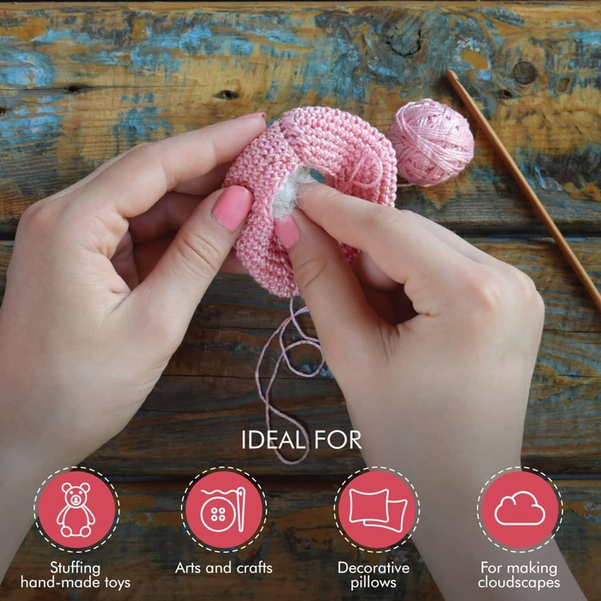 Polyester fiber fill stuffing a small crocheted project, hands holding pink yarn