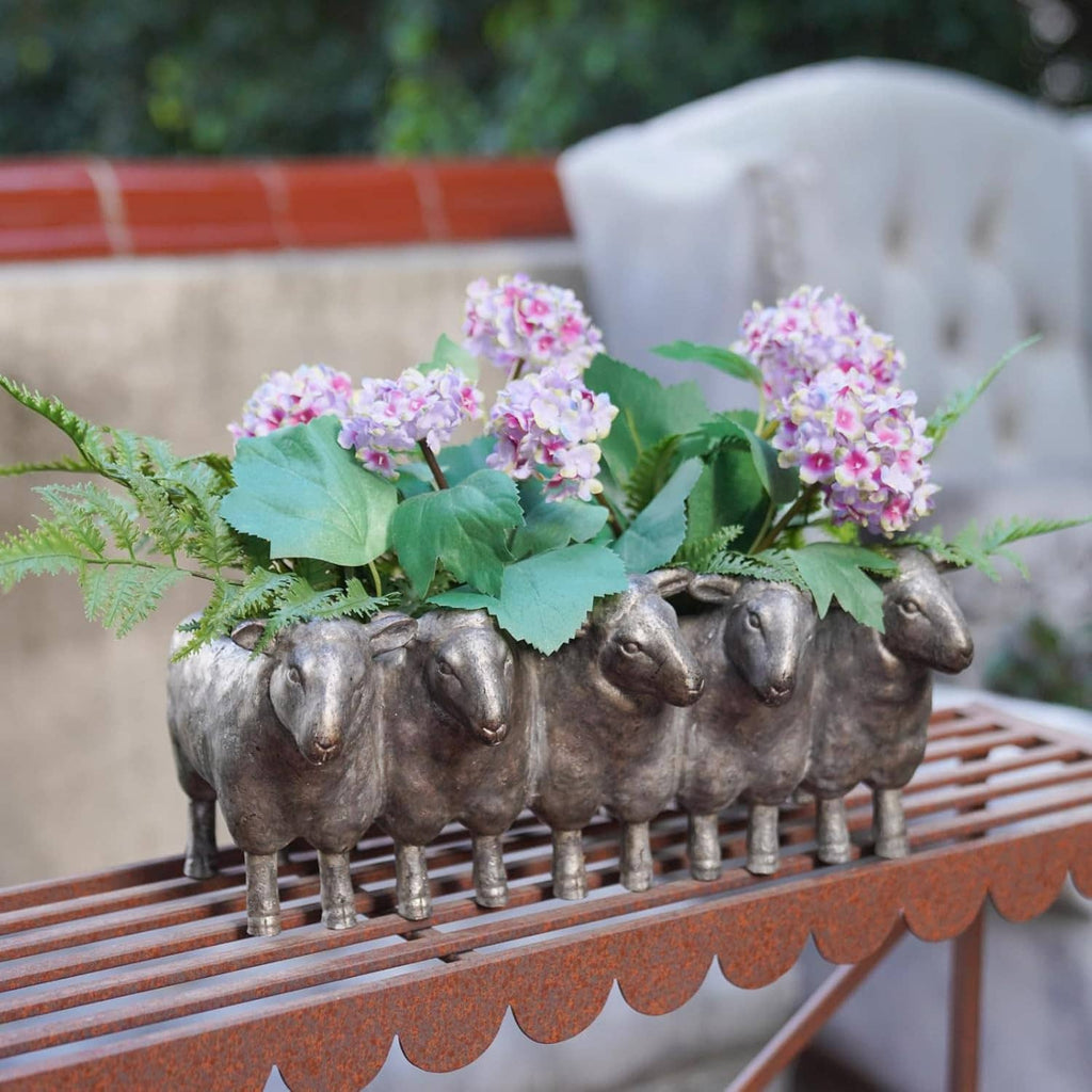 Dark gray resin sheep planter pot filled with purple and green flowers