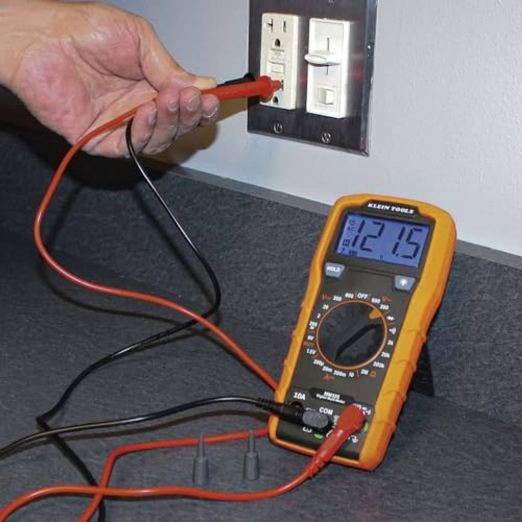 Digital multimeter with orange casing connected to red and black probes for wall testing.