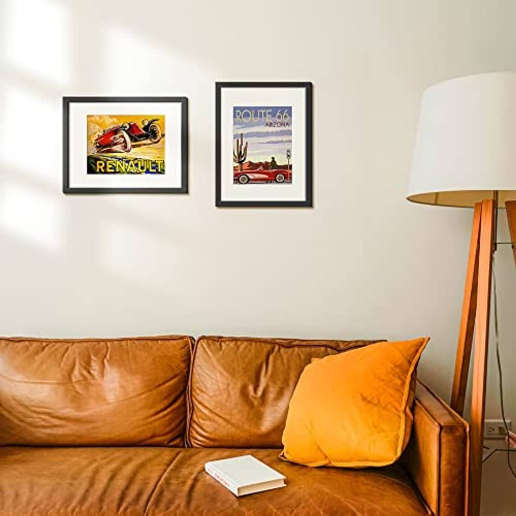 Two black picture frames with colorful prints on a wall above a sofa