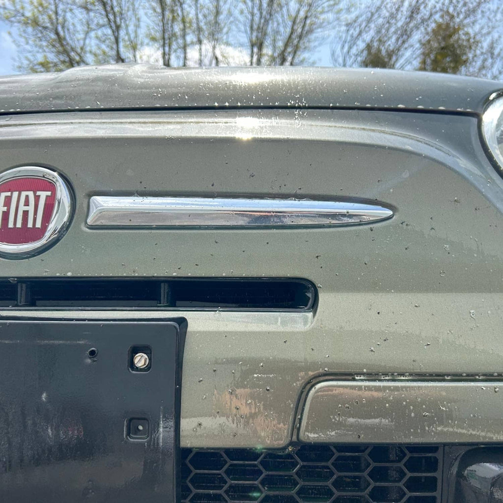 Car front with visible bug splatters and residue on the grille area