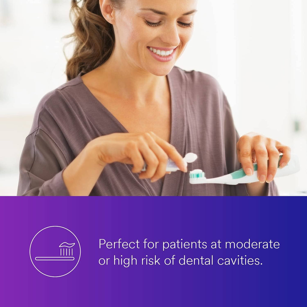Anti-cavity fluoride toothpaste on toothbrush, squeezed by smiling woman