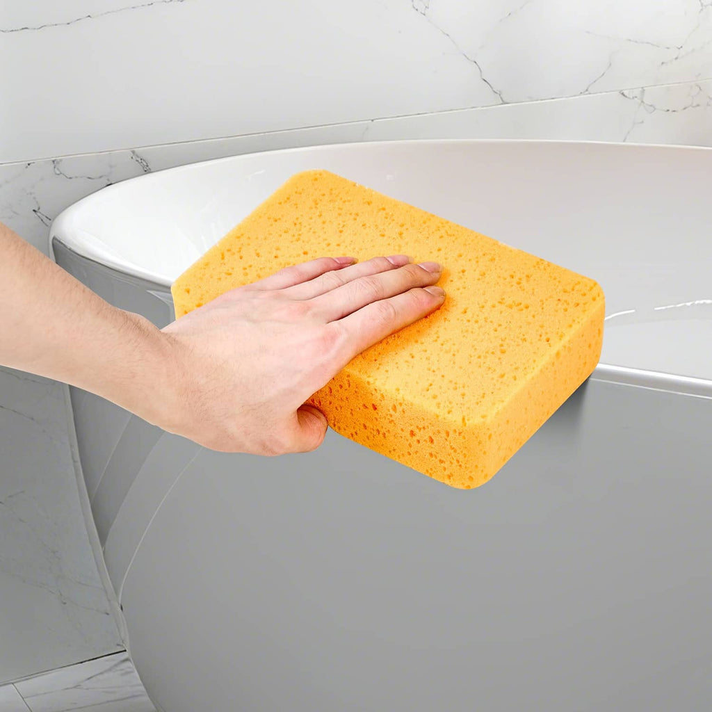 Orange-yellow foam grout sponge in hand cleaning a toilet bowl