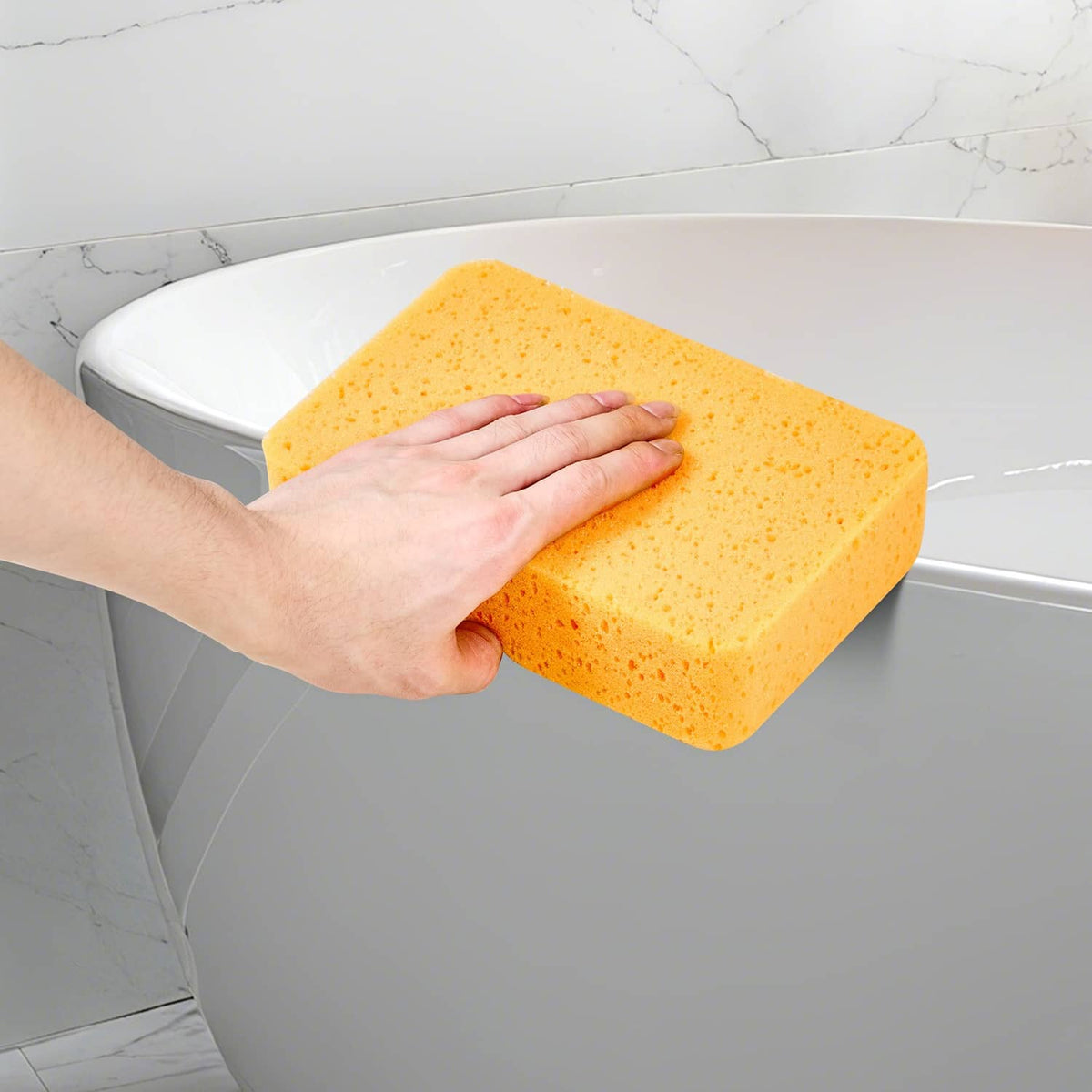 Orange-yellow foam grout sponge in hand cleaning a toilet bowl
