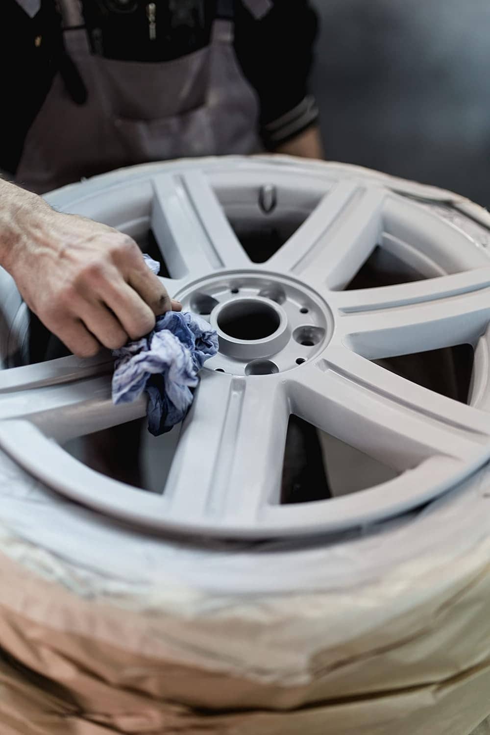 Worker wiping a blasted wheel rim with a cloth