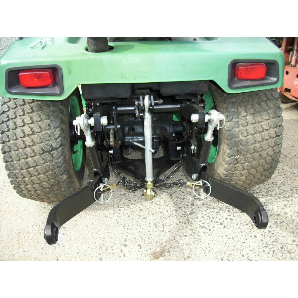 Rear 3-point hitch installed under tractor; black arms with silver lift rod and chains