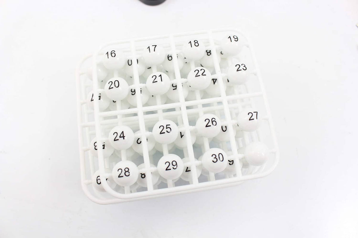 White bingo balls in a transparent bingo cage with numbered grid