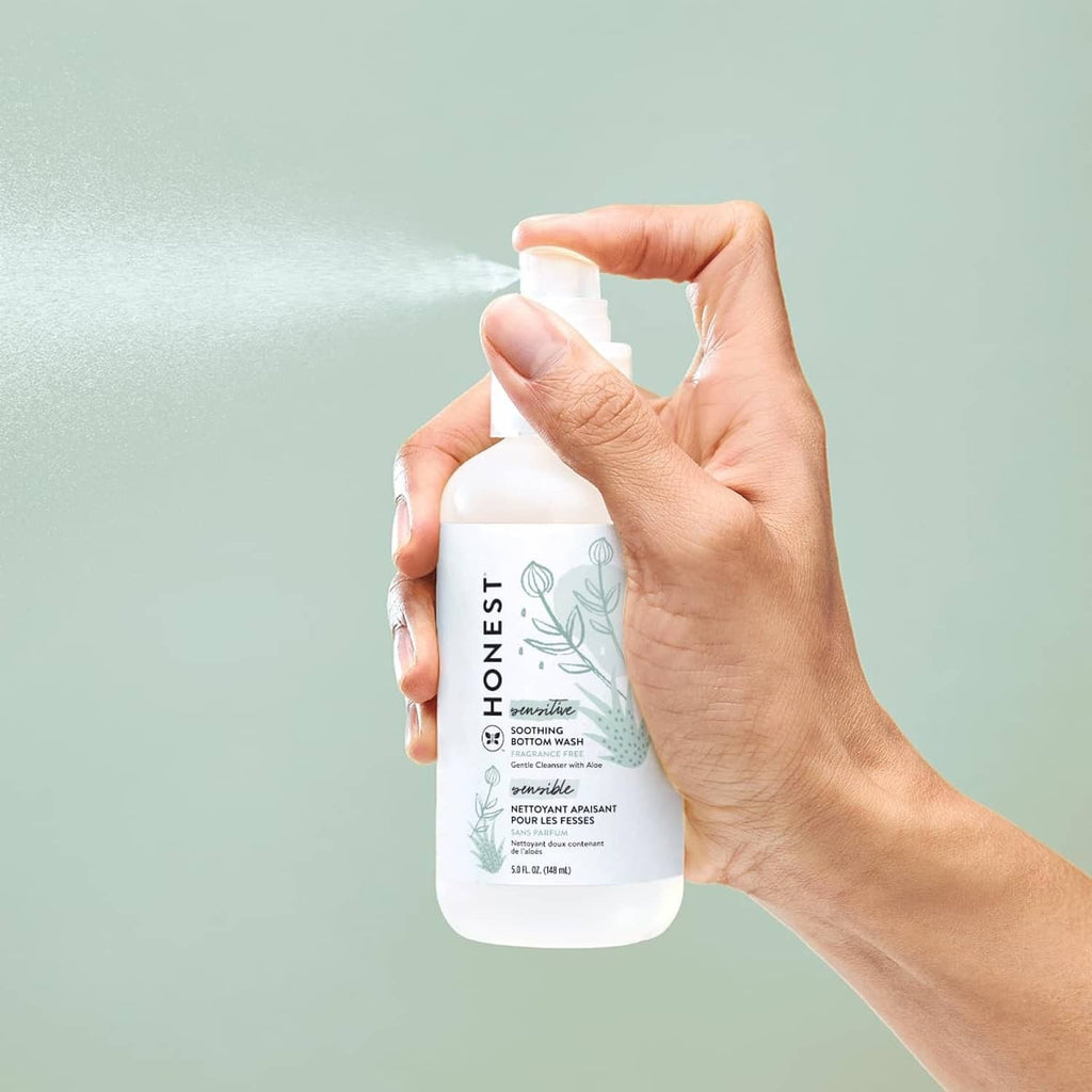 The Honest Company soothing baby bottom wash bottle held in a hand, white pump