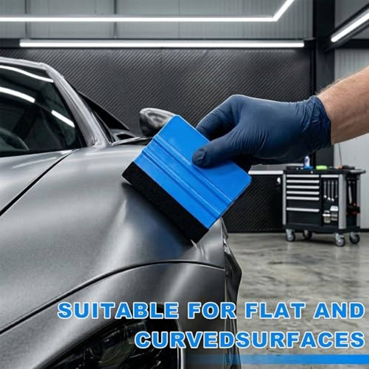 Gloved hand holding a blue felt-edge squeegee while applying window film on a car