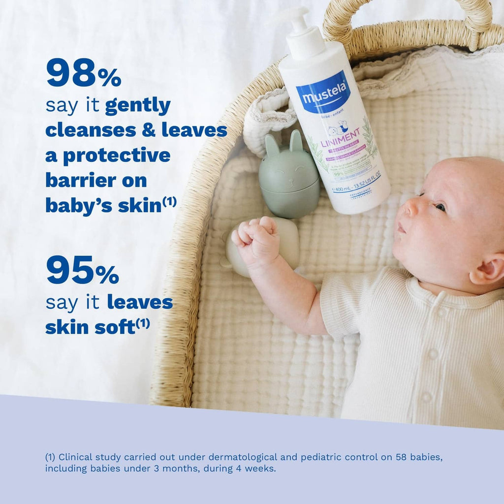 Mustela Liniment baby cleanser bottle beside sleeping baby on soft blanket