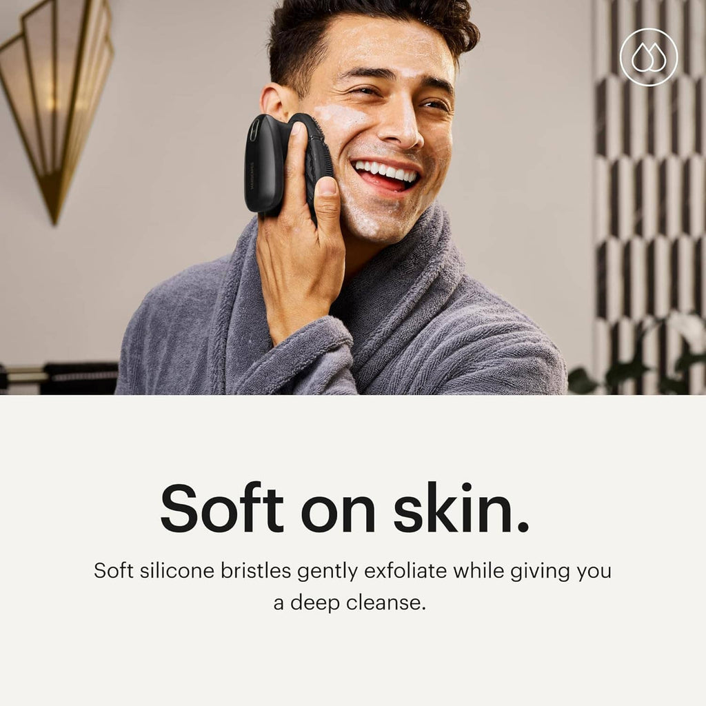 Man smiling while using electric silicone face scrubber on his face