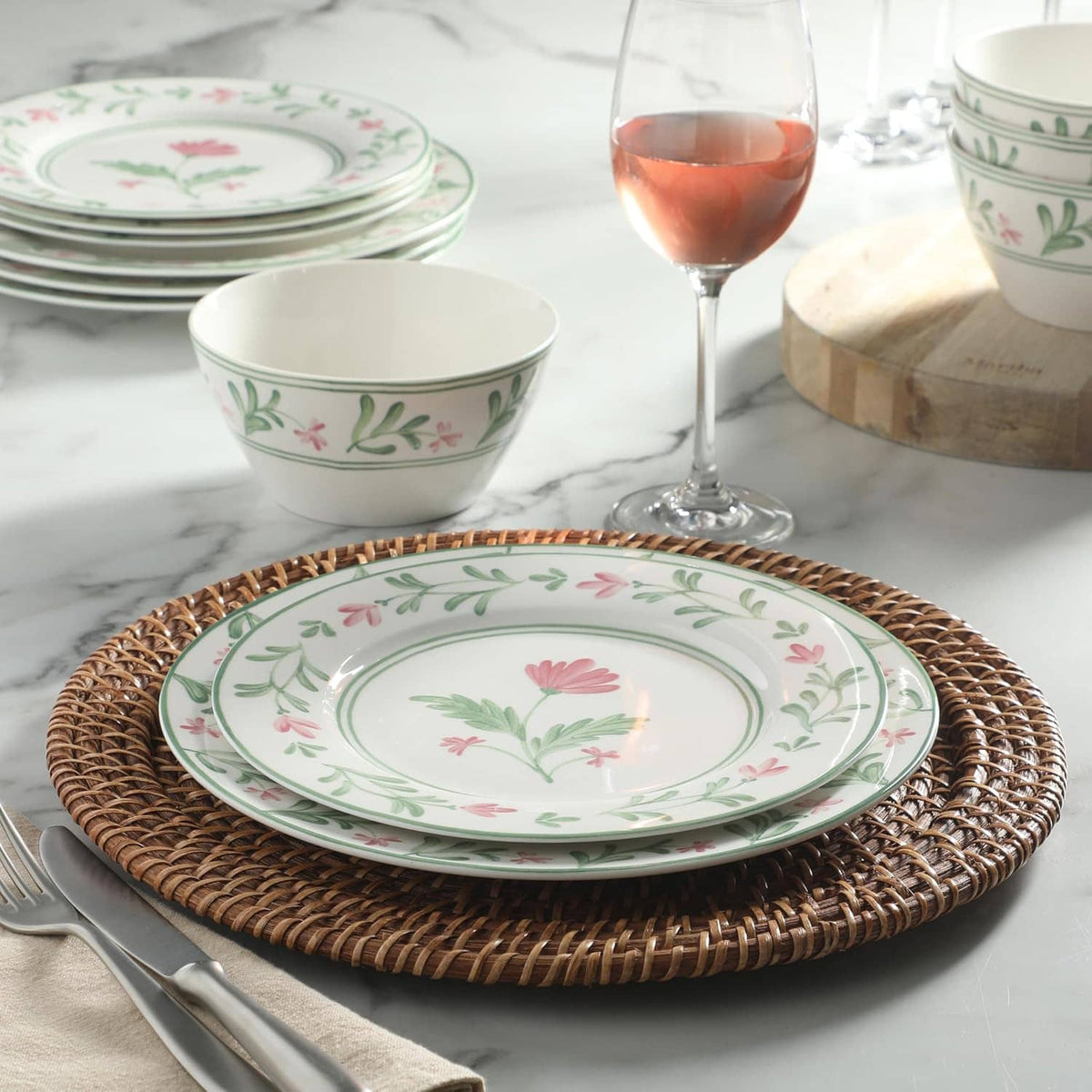 Floral dinner plate with green border and pink flowers, with matching bowl and plates nearby
