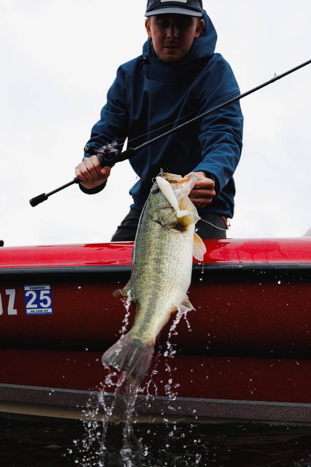 Angler holds a large bass with splashing water, fishing line visible