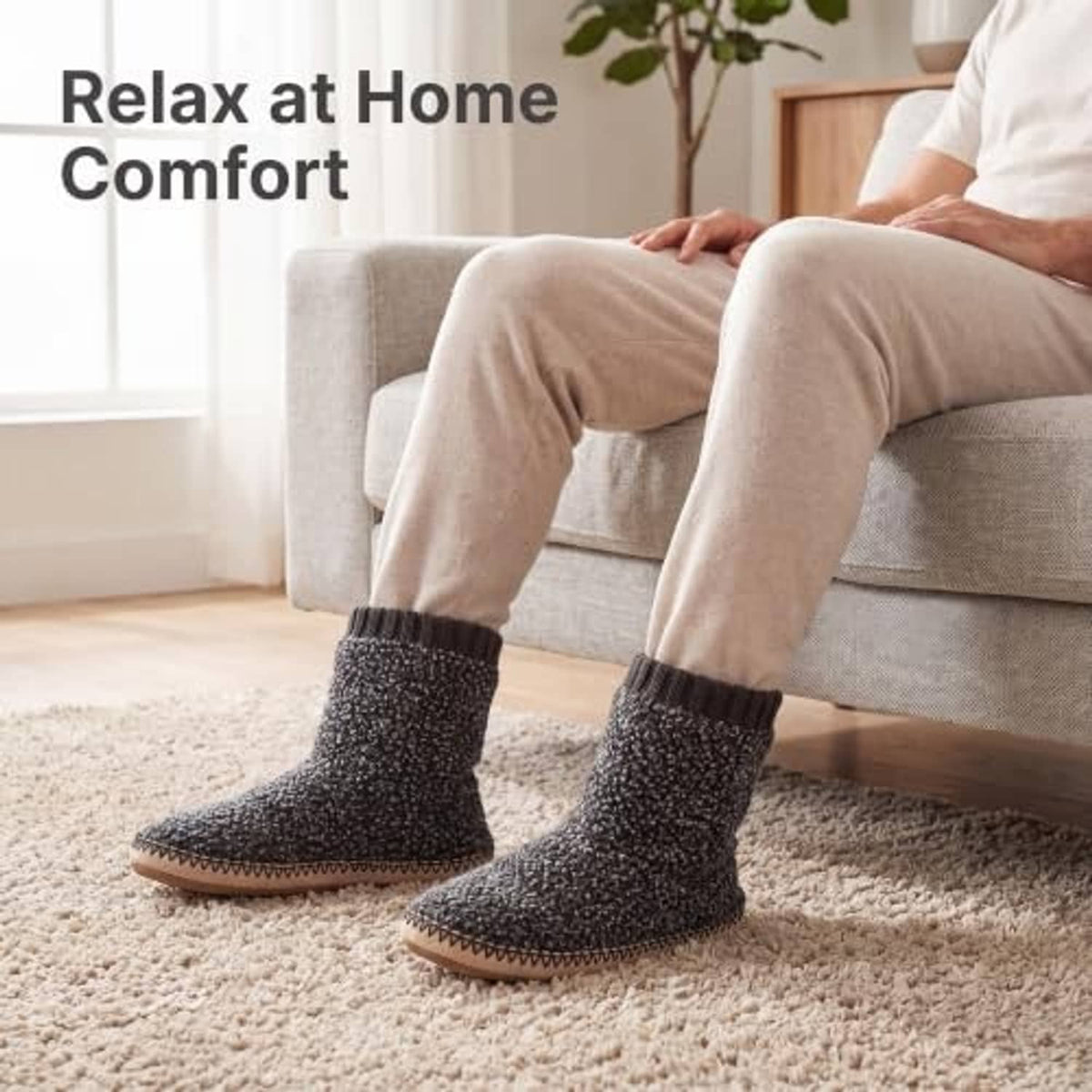 Men's grey fuzzy boot slippers on carpet with ribbed cuffs and tan stitched outsole