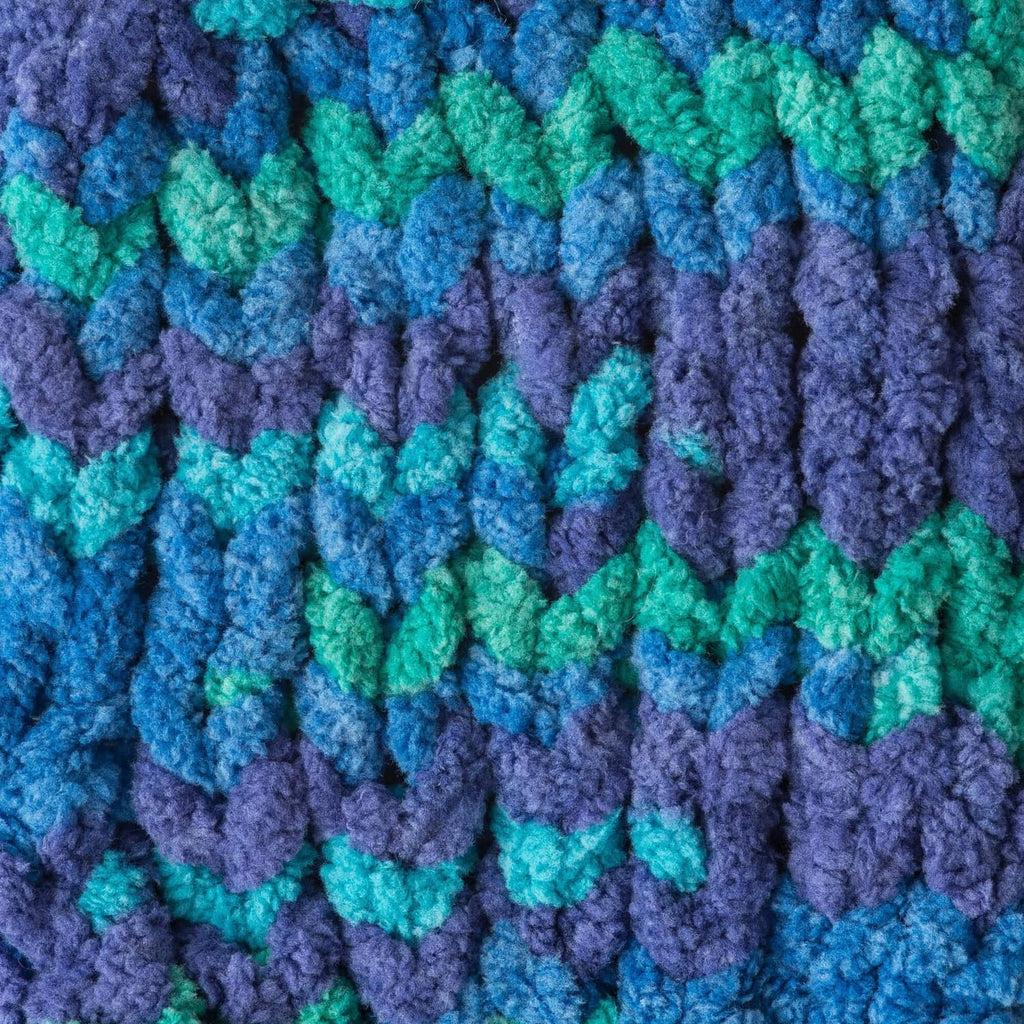 Close-up of variegated super bulky yarn texture in blue, teal, and purple