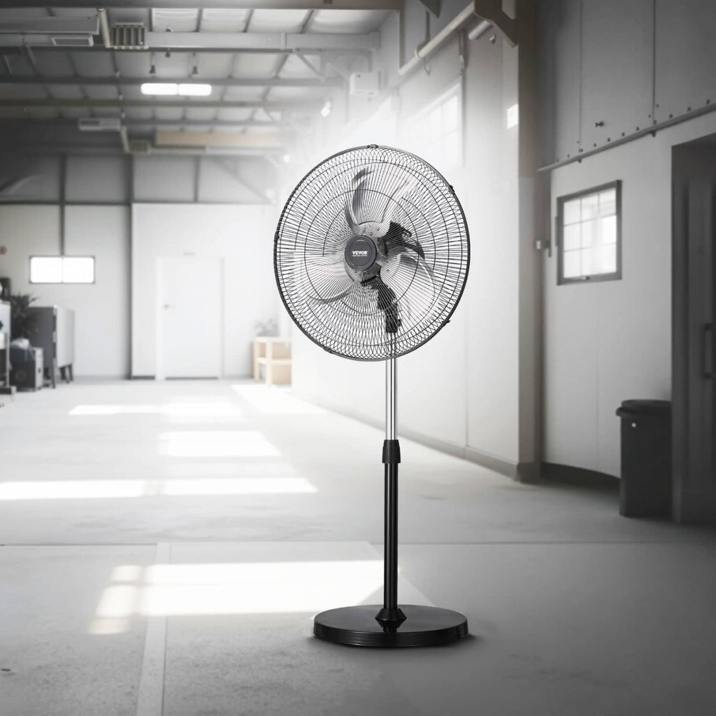 Black industrial pedestal fan with circular wire grille and tall stand in a workshop