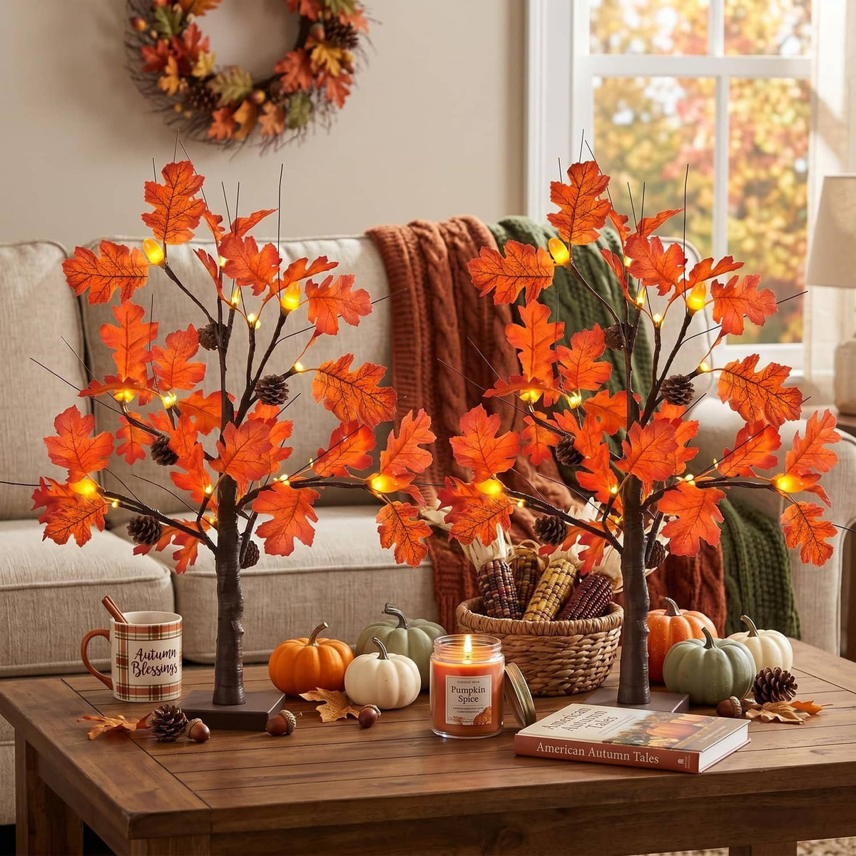 Lighted fall acorn tree decorations with orange leaf lights on a sofa table with gourds