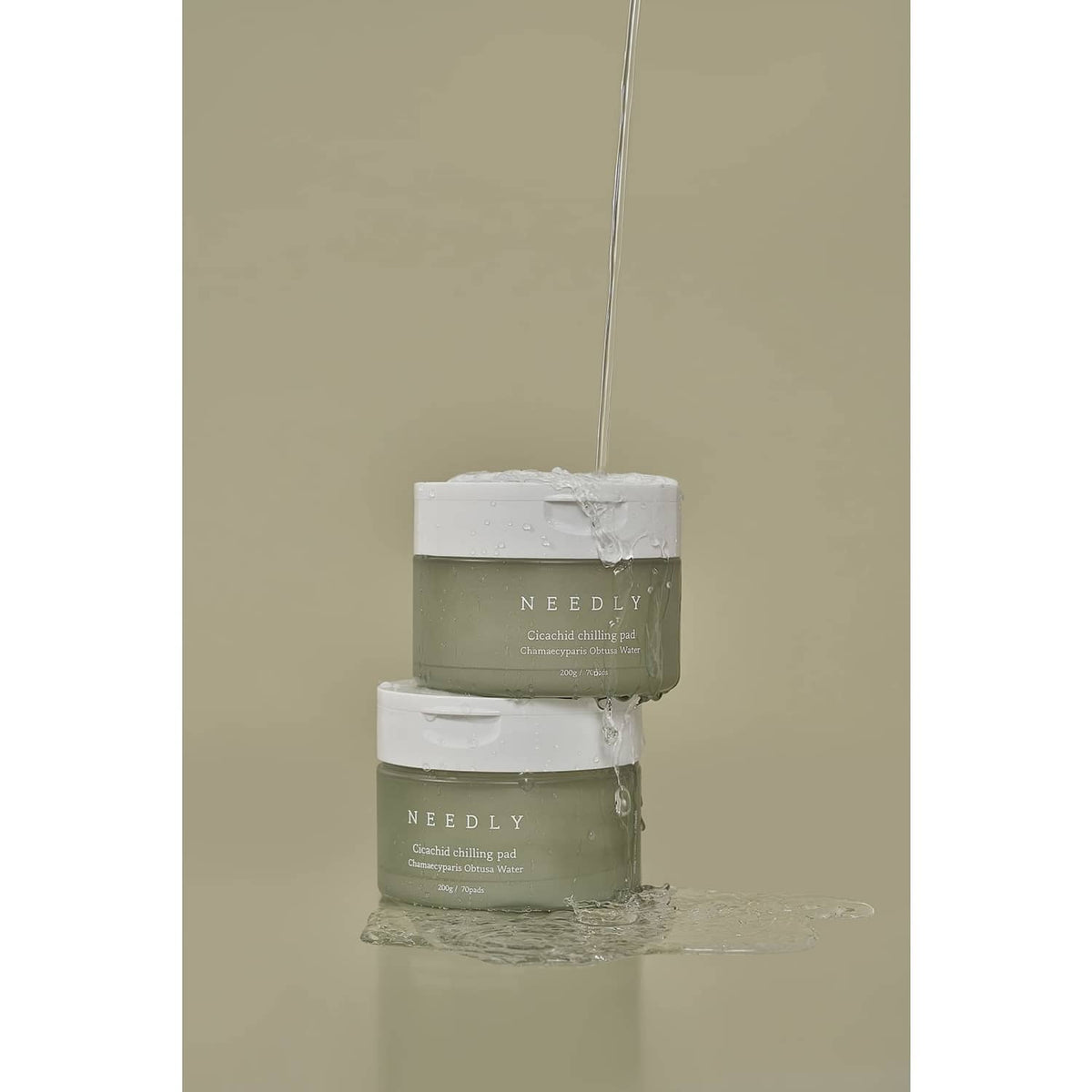 NEEDLY cleansing pad jars with water pouring over the containers
