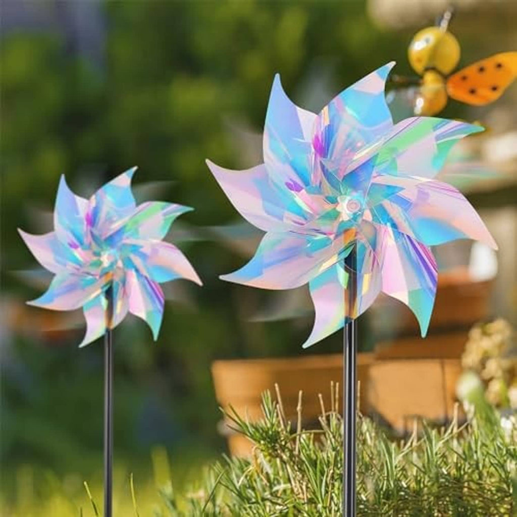Reflective rainbow pinwheel wind spinners with black stakes in outdoor grass